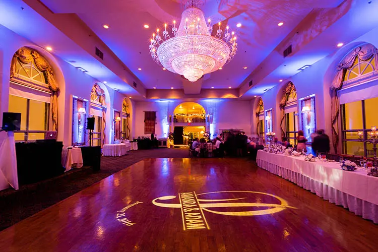 Violet uplighting surrounds an elegant ballroom and chandelier
