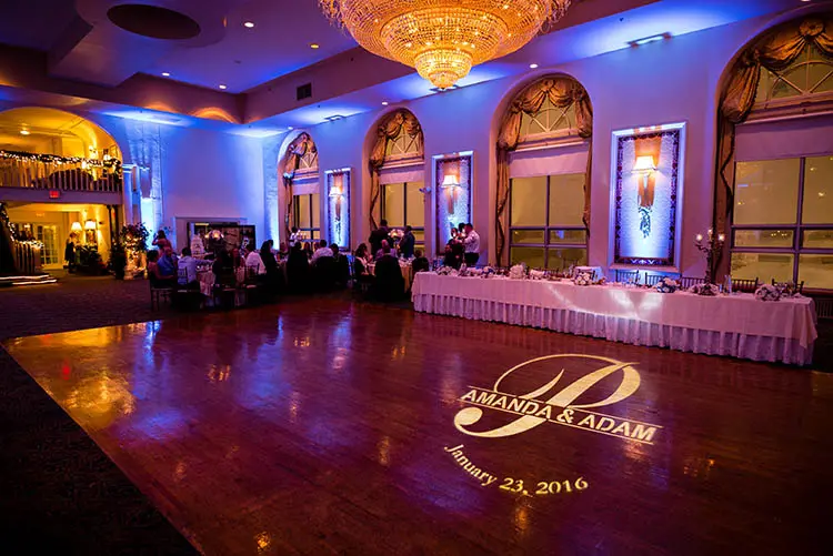 Ballroom walls washed in violet beside a monogrammed dance floor