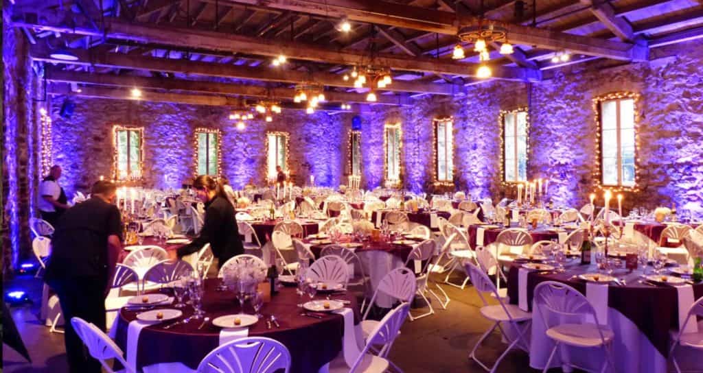 Violet lighting among rustic beams and reception tables