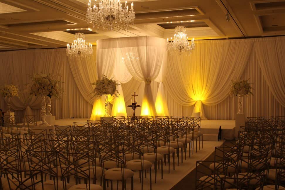 Golden lighting frames white ceremony drapery
