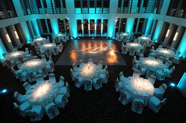 Turquoise architectural lighting surrounds ballroom tables