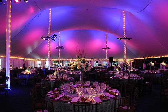 Pink and violet light fills a white wedding tent